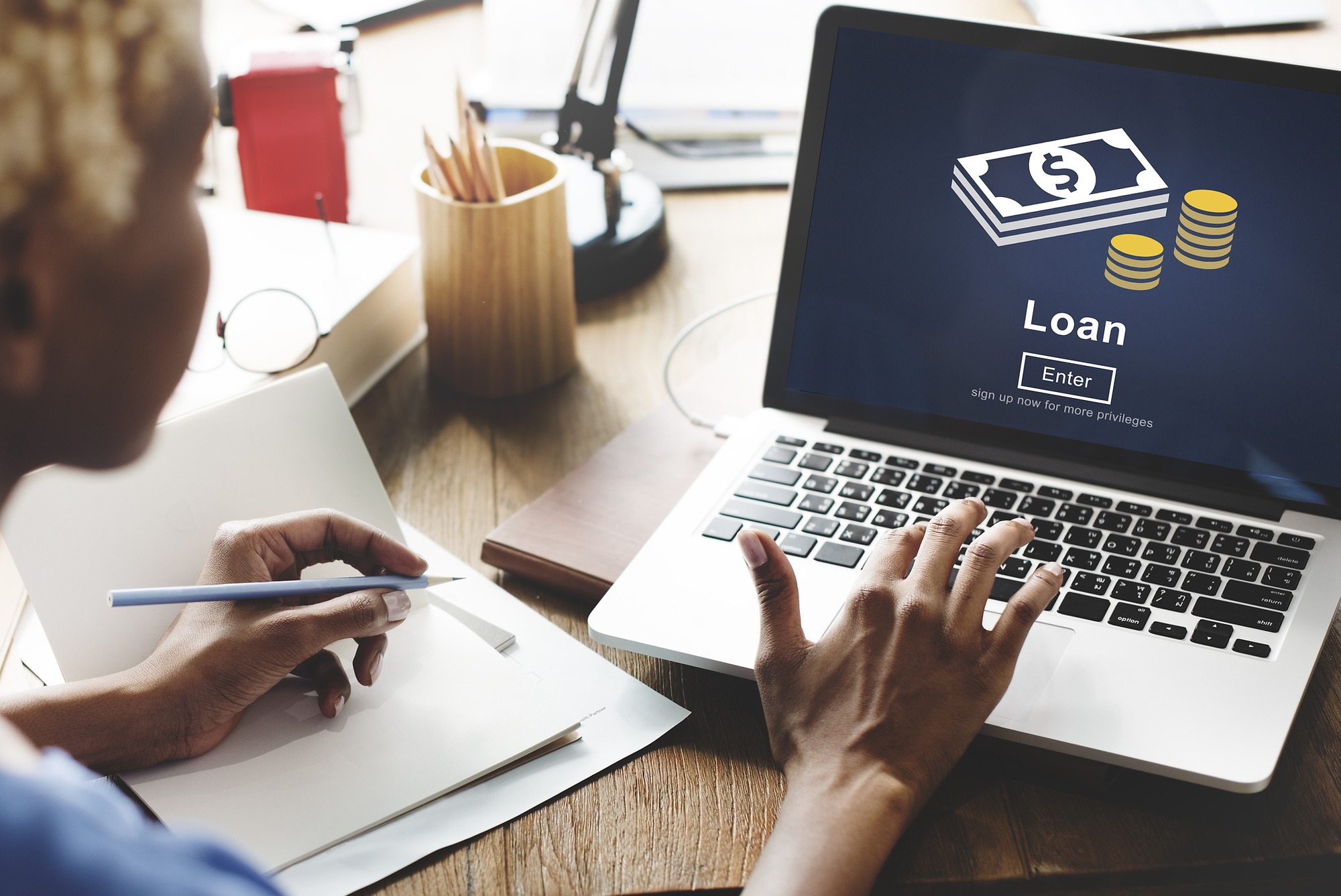 Person pressing a key on a laptop showing the word loan