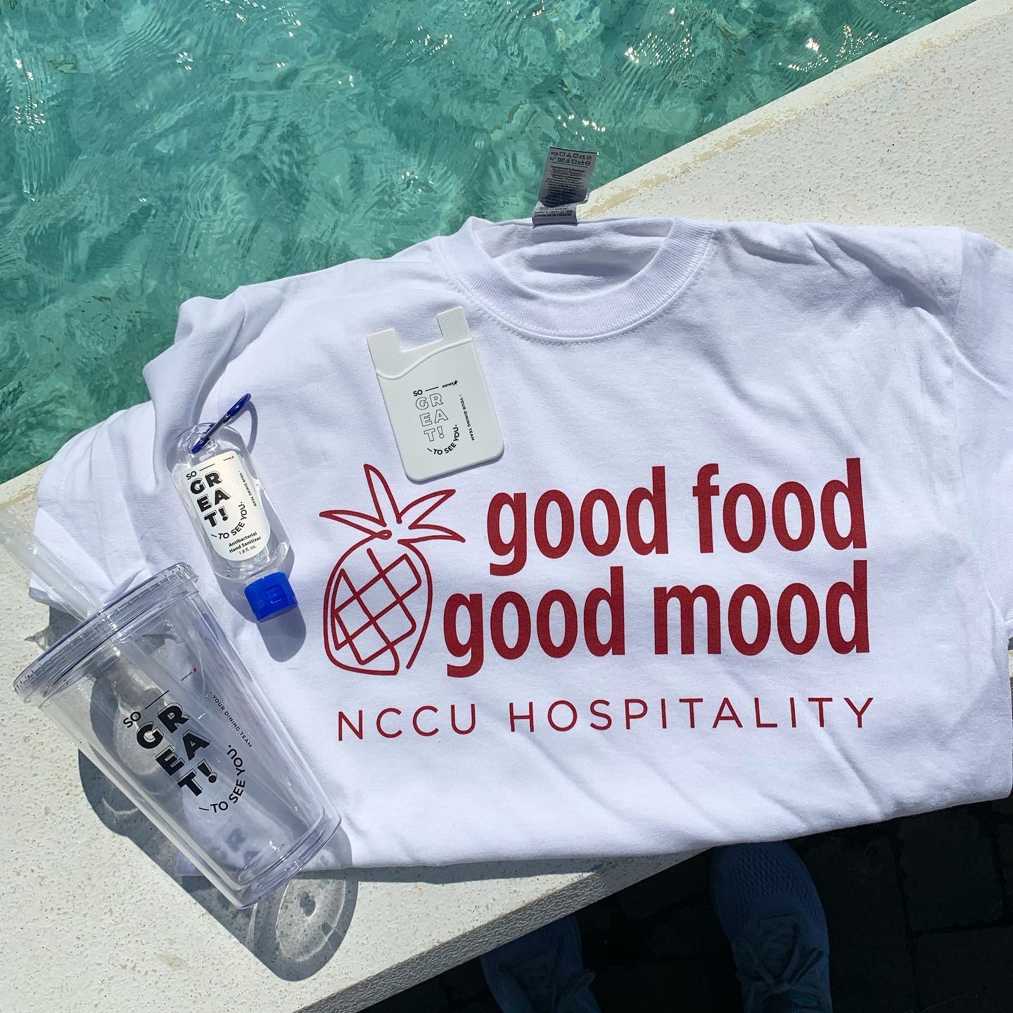 NCCU Hospitality shirt, cup, and hand sanitizer sitting on a table.