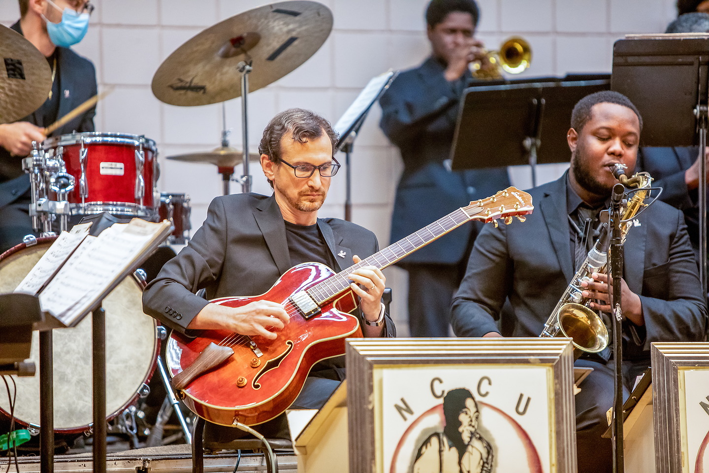 Jazz band performs with saxophone, trumpet, and guitar
