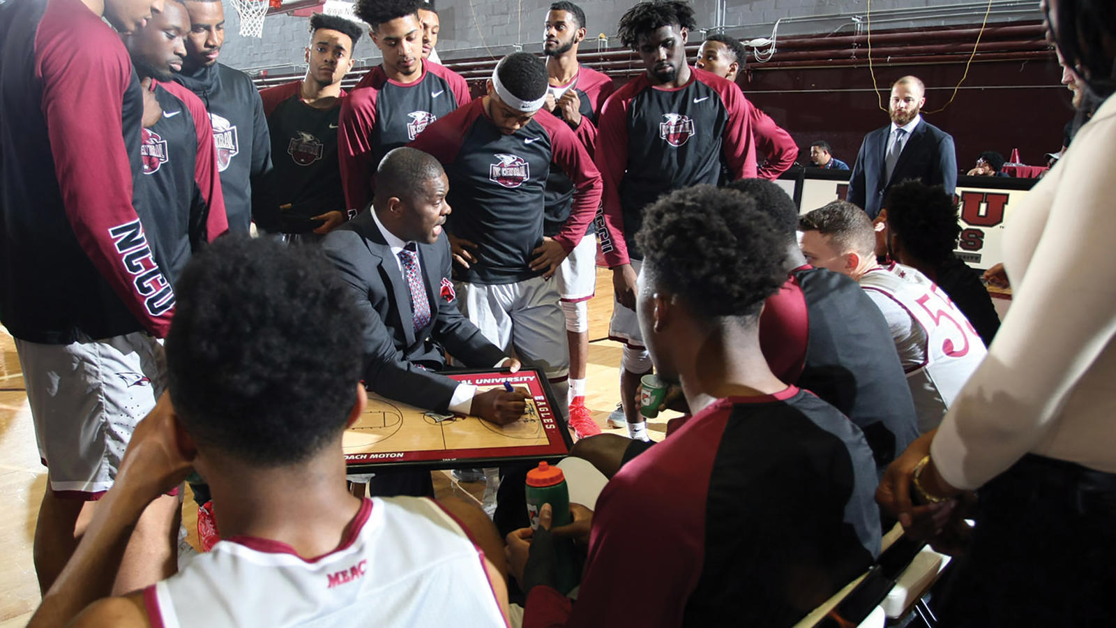 The NCCU Men's basketball team huddles around their coach as he gives a passionate speech 