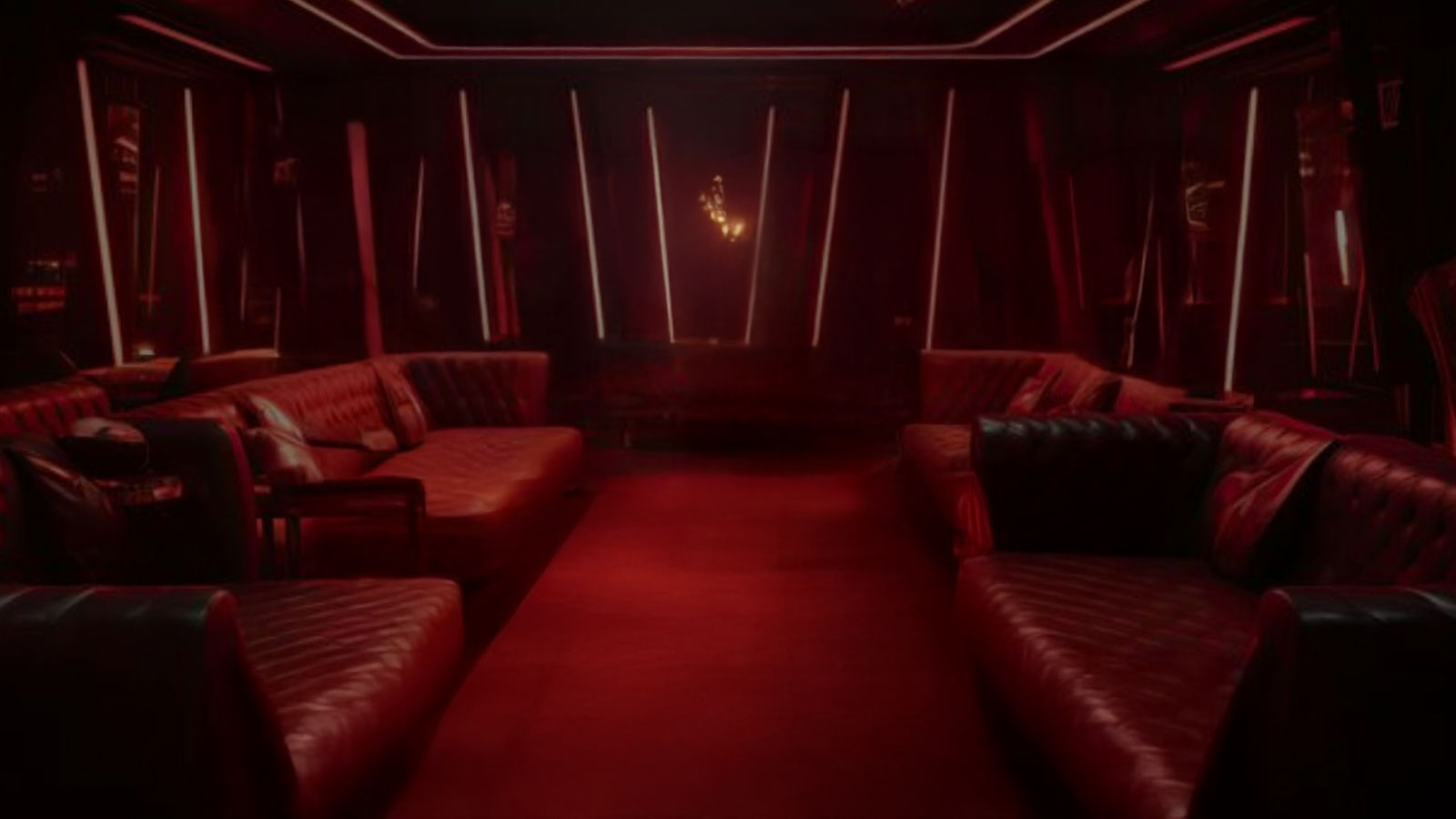  A room with maroon lighting and a plush, leather couch along each wall.