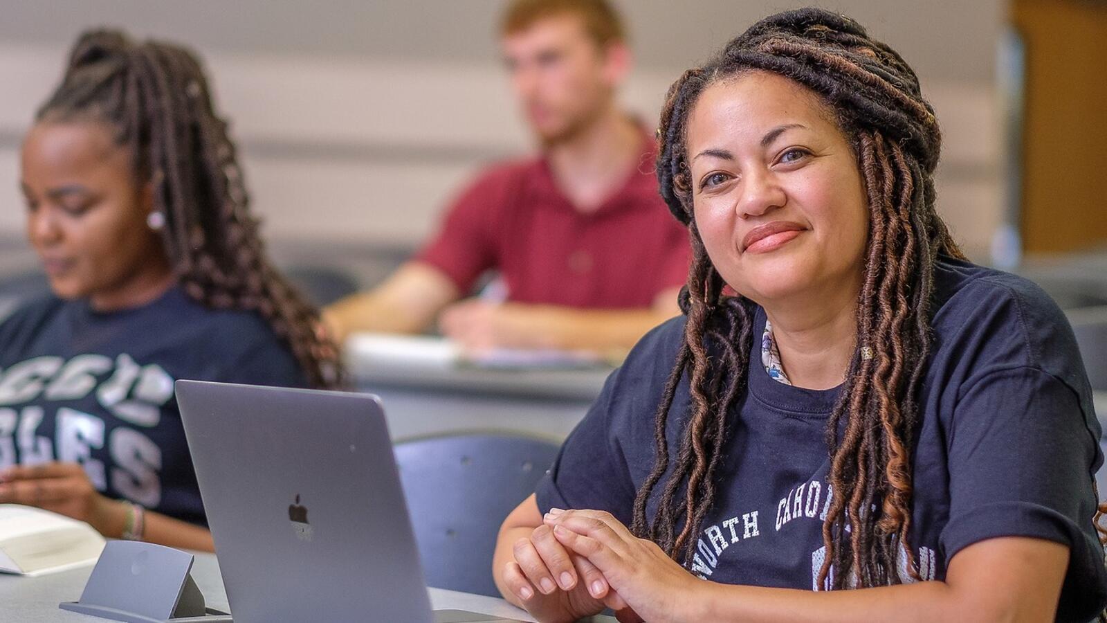 student on laptop, smiling at the camera