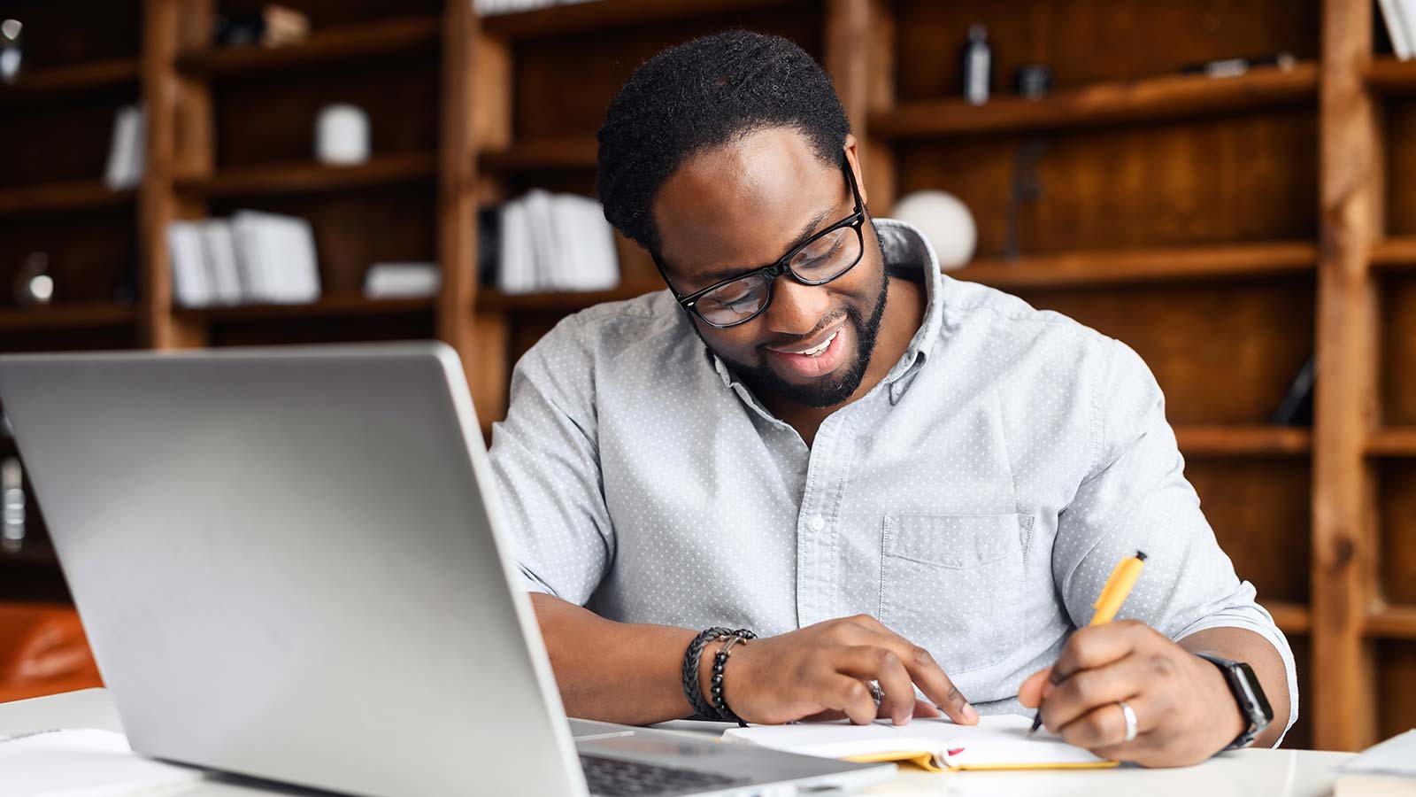 person taking notes in front of laptop
