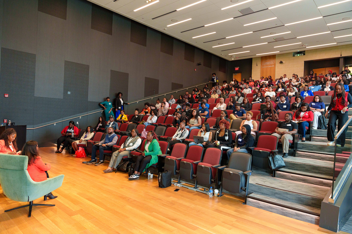 a large auditorium with two speakers speaking to students