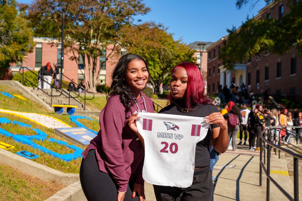 Image of two women holding an NCCU jersey