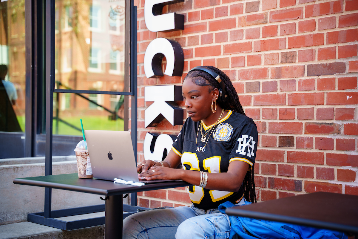 Woman with headphones sitting and looking at a laptop
