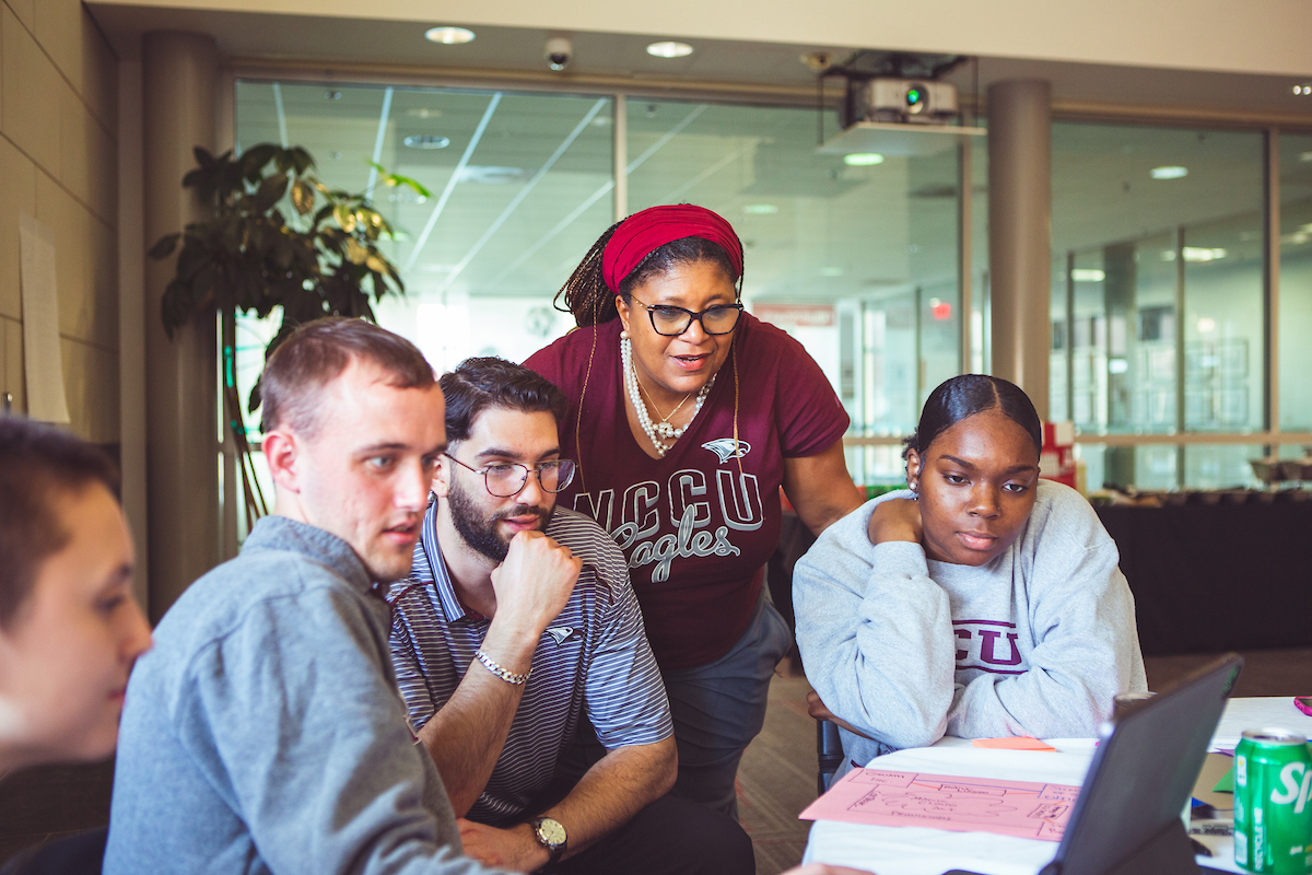 A group of five people looking at a laptop