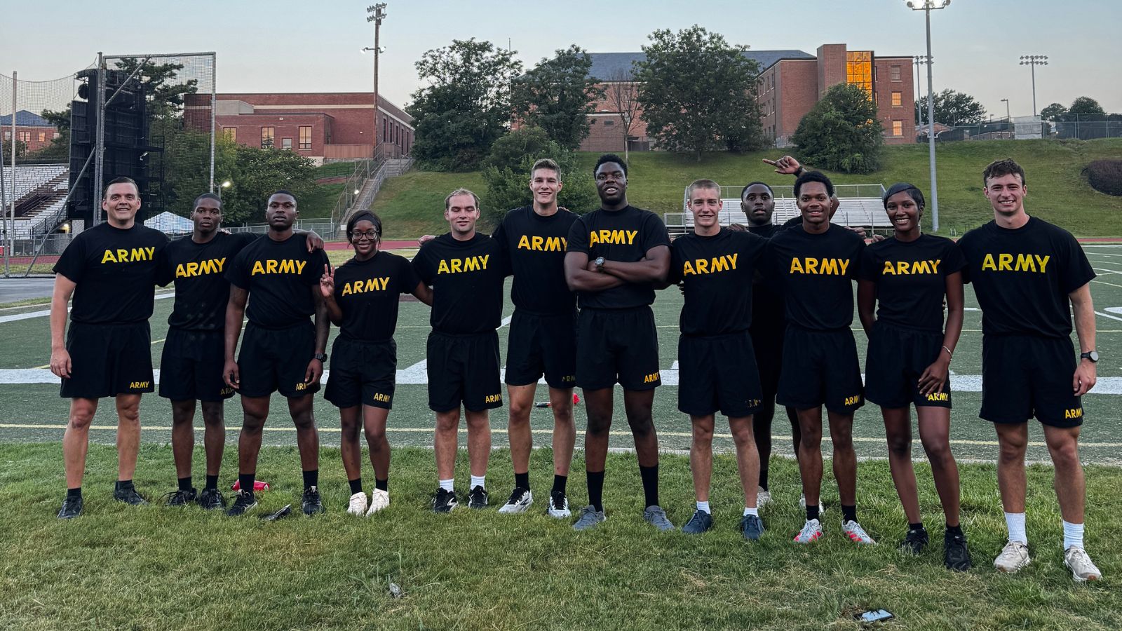 North Carolina Central University and DUKE Army ROTC cadets pose together on an outdoor athletic field wearing black and gold Army athletic uniforms.