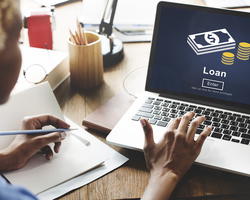 Person pressing a key on a laptop showing the word loan