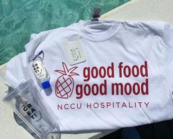 NCCU Hospitality shirt, cup, and hand sanitizer sitting on a table.
