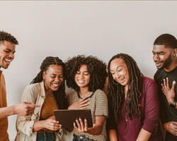 Group of people smiling and laughing watching a tablet.