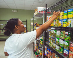 student placing canned food on a shelf