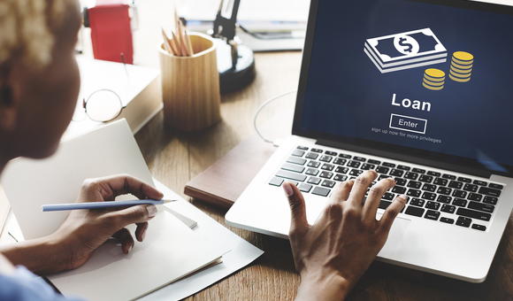 Person pressing a key on a laptop showing the word loan
