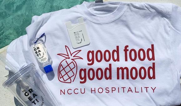 NCCU Hospitality shirt, cup, and hand sanitizer sitting on a table.