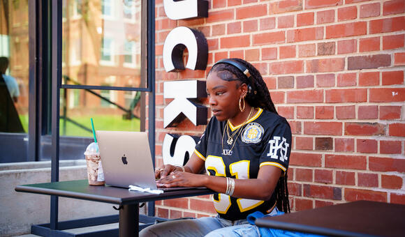 Woman with headphones sitting and looking at a laptop