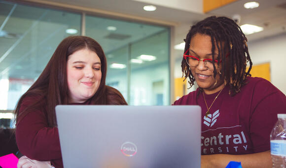 Two students looking at a laptop