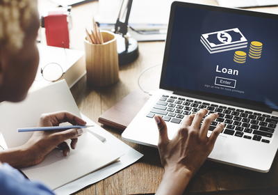 Person pressing a key on a laptop showing the word loan