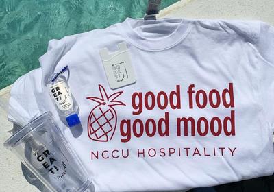 NCCU Hospitality shirt, cup, and hand sanitizer sitting on a table.