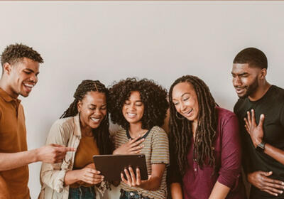Group of people smiling and laughing watching a tablet.