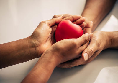 Two sets of hands holding a small toy heart