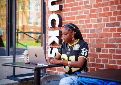 Woman with headphones sitting and looking at a laptop